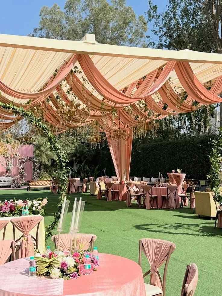Pastel-themed outdoor wedding lawn setup with draped canopy.