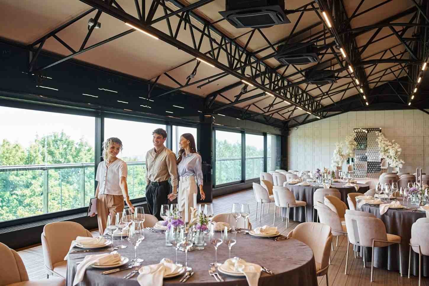 Guests exploring a modern indoor wedding venue with elegant table arrangements and spacious event interiors.