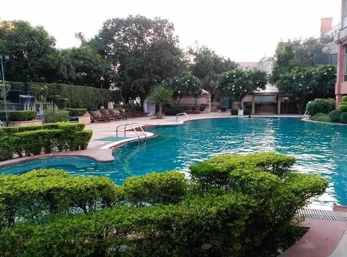 Luxury outdoor swimming pool at The Ashok Hotel, New Delhi, India: crystal-clear turquoise waters in a curved infinity-edge pool with jacuzzi spillover.