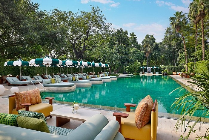 Luxury Ambience Island Lagoon Swimming Pool: vibrant turquoise resort pool surrounded by lush tropical greenery, green candy-striped umbrellas shading circular loungers and ottomans.