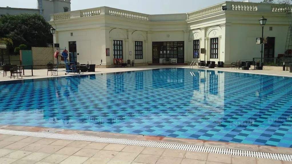 DLF Club Swimming Pool in DLF Phase 1 Gurgaon India: elegant rectangular mosaic-tiled lap pool with vibrant blue square patterns and crystal-clear reflections.