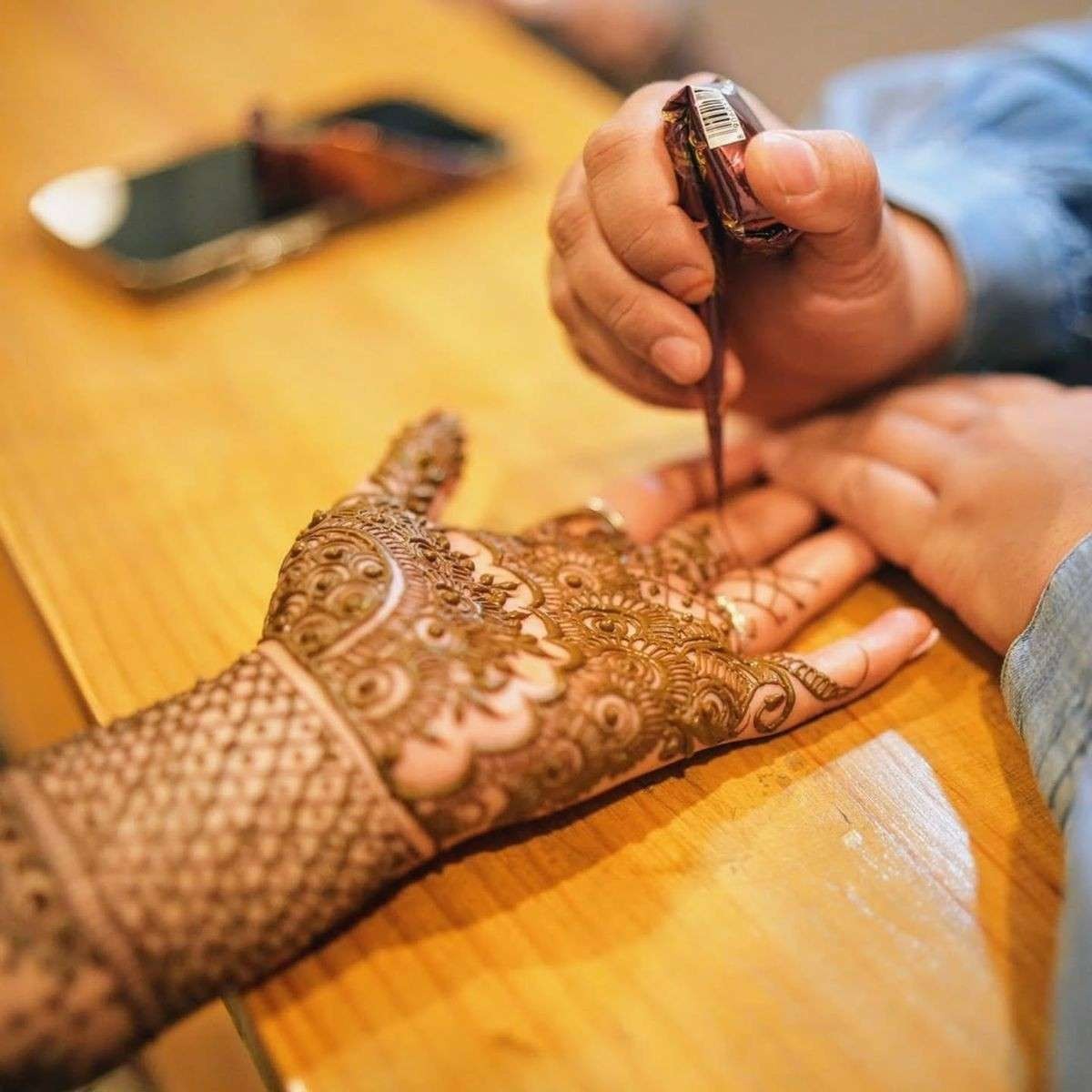 Intricate bridal mehndi design being applied on bride’s hand with traditional henna art for wedding ceremony in Delhi NCR.