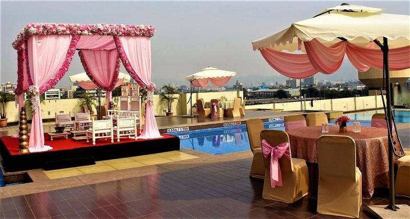 Elegant rooftop engagement party setup with pink floral stage decor, poolside seating arrangement, and romantic outdoor celebration ambiance.