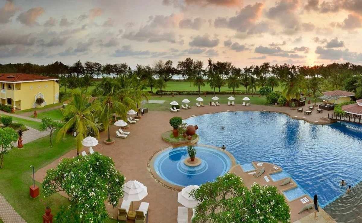 Scenic outdoor swimming pool at The Lalit Golf & Spa Resort Gurgaon surrounded by lush greenery and palm trees