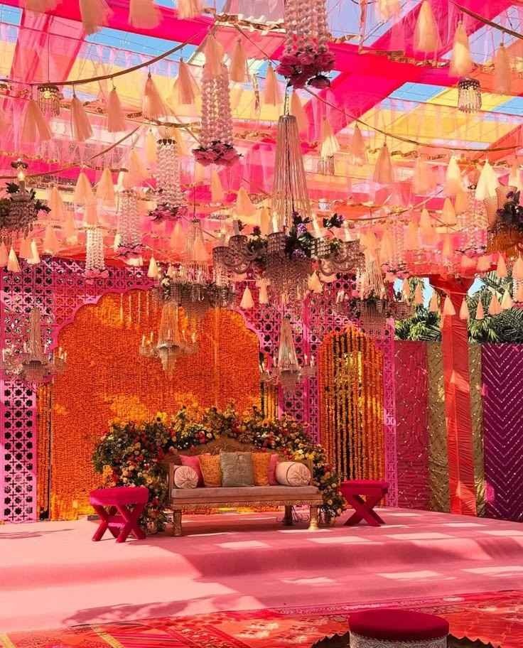 Elegant pink floral wedding stage with vibrant canopy and luxurious décor at an outdoor venue.