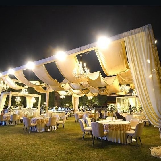 Premium outdoor wedding lawn venue with elegant canopy décor, crystal chandeliers, round table seating, and luxury banquet setup for weddings in Delhi NCR.