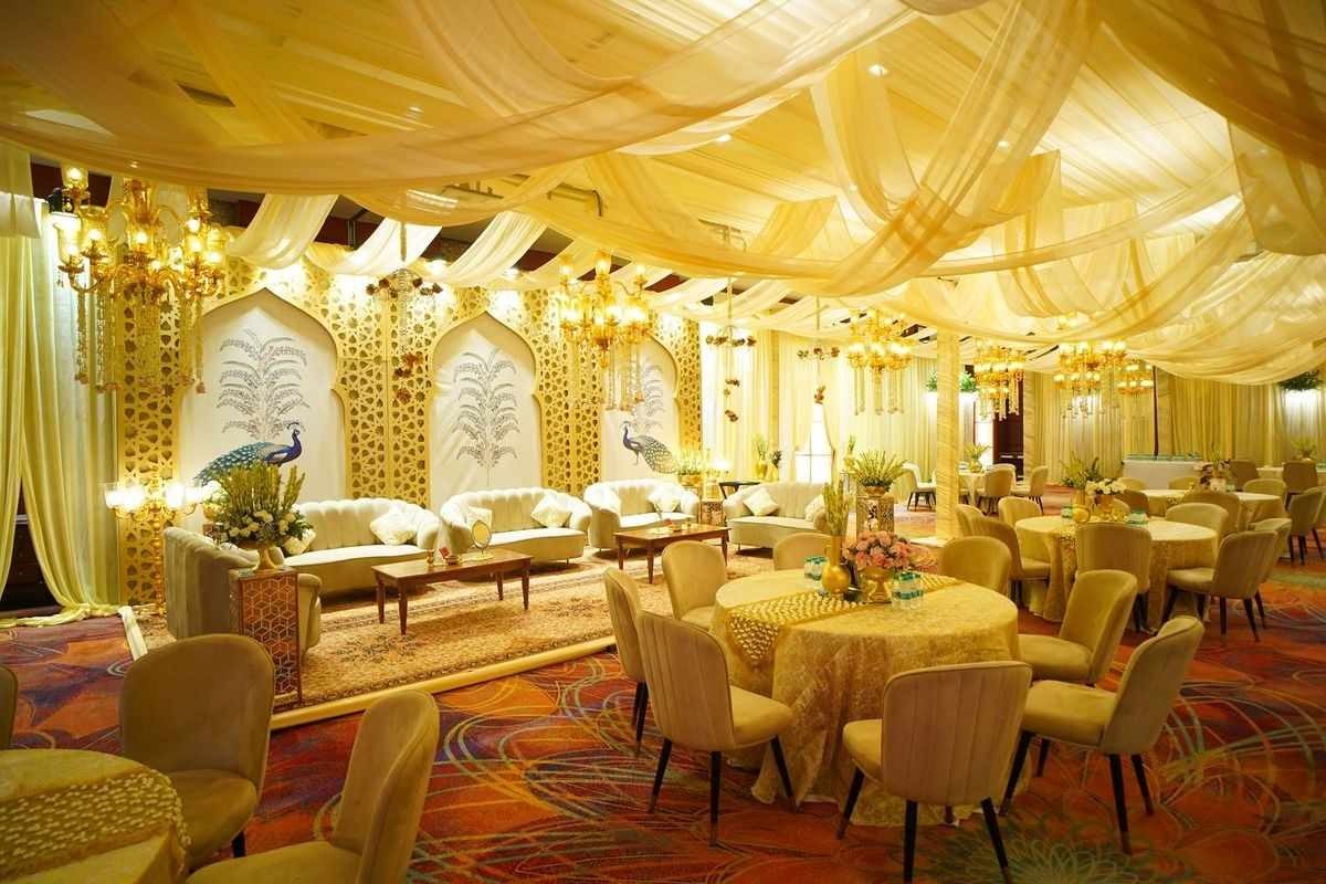 Luxury indoor wedding banquet hall with elegant stage décor, crystal chandeliers, premium seating, and floral arrangements for wedding receptions in Delhi NCR.