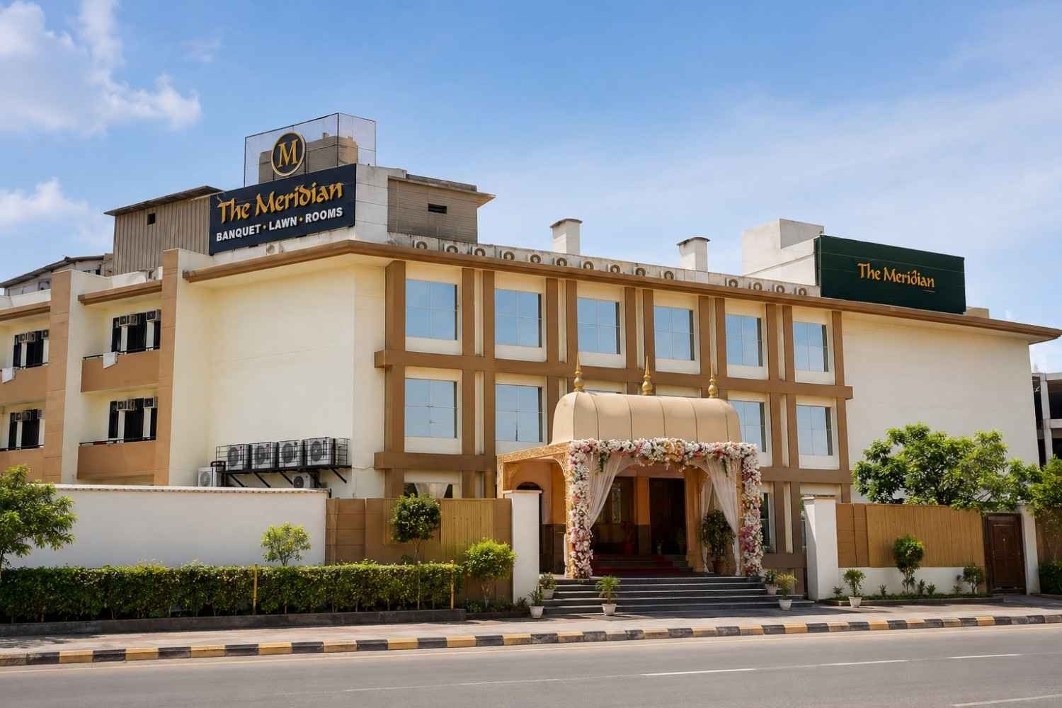 Front exterior view of The Meridian Banquet Lawn & Rooms in Greater Noida, featuring a modern banquet hall with elegant architecture, spacious entrance, and event venue facade.